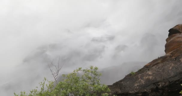 Detail von Wasser, das beim Sturz vom Wasserfall in Felsen spritzt. Wasserdampf steigt mit Streuung auf. Vögel, Vegetation und Felsstrukturen im Vordergrund. Cordoba, Argentinien — Stockvideo