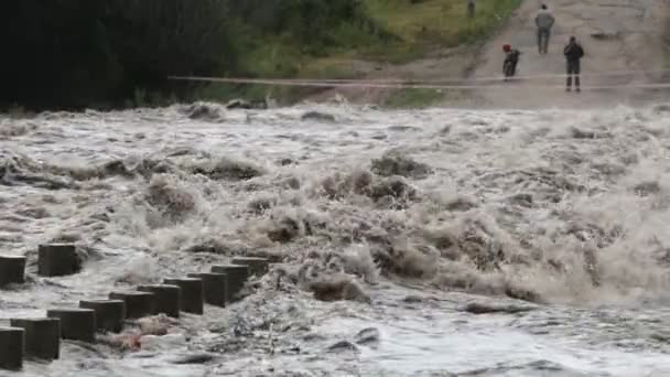 Movimento lento da ponte inundada. Detalhe de trilhos enquanto forte rio marrom turbulento passa sobre a construção. Brunches, trush aparecem na corrente do rio. Inundação em Córdoba, Argentina — Vídeo de Stock