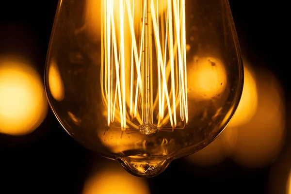 Macro shot of glowing Edison lamp. Lamp with abstracted lines on black background.