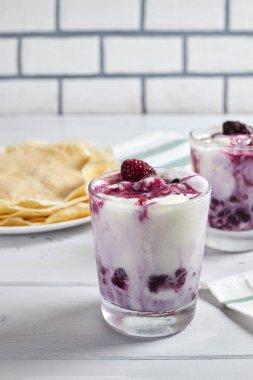 Vanilyalı dondurma ve böğürtlen soslu lezzetli tatlı ve arka planda iştah açıcı krepler. Seçici odak.