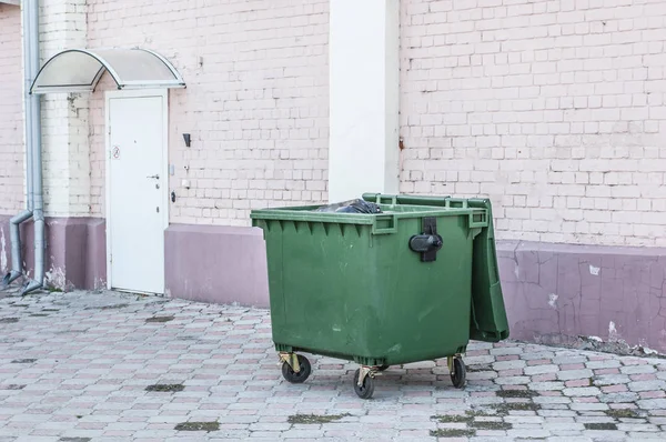 Dumpster on the brick wall background. Garbage bin near building