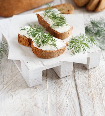 Sandviç ile krem peynir ve ahşap bir masa üzerinde taze dereotu