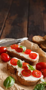 Bruschetta krem peynir, domates ve fesleğen ahşap bir masa üzerinde