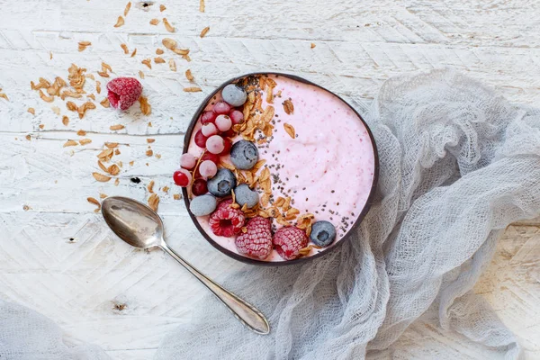 Wild berries smoothie bowls topped with frozen berries and granola