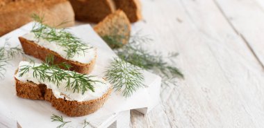 Sandviç ile krem peynir ve ahşap bir masa üzerinde taze dereotu