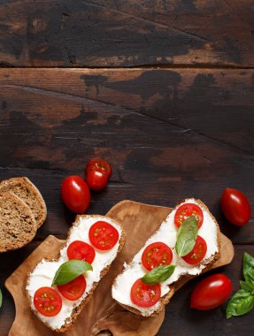 Bruschetta krem peynir, domates ve fesleğen ahşap bir masa üzerinde