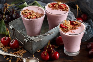 Bir bardak taze kiraz ve granola ile tepesinde kiraz smoothie