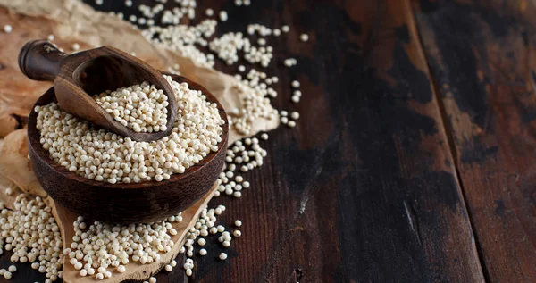 Raw White Sorghum grain in a bowl on a wooden table