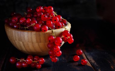 Olgun kırmızı kuş üzümü meyveleri koyu arka plan üzerinde bir kasede