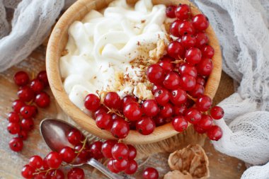 Kırmızı kuş üzümü ve top bir kase yoğurt görüntülemek