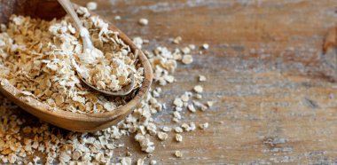 Bir kaşık ile ahşap bir kasede haddelenmiş yulaf yakın çekim