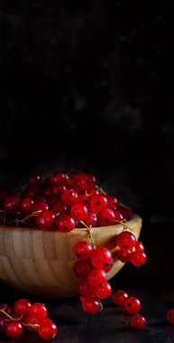 Olgun kırmızı kuş üzümü meyveleri koyu arka plan üzerinde bir kasede