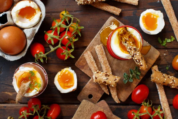 ぱりっとしたパンと木製のテーブルの上のトマトと半熟卵 — ストック写真
