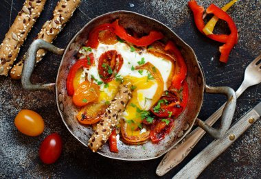 Sahanda yumurta dolmalık biber ve domates üzerinde eski bir kızartma tavası 