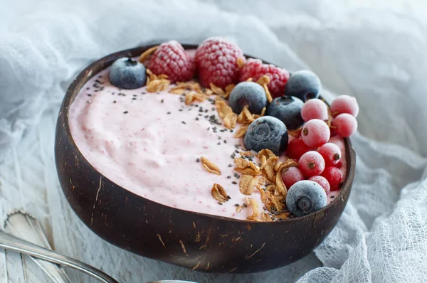 Wild berries smoothie bowls topped with frozen berries and granola