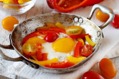 Sahanda yumurta dolmalık biber ve domates üzerinde eski bir kızartma tavası 