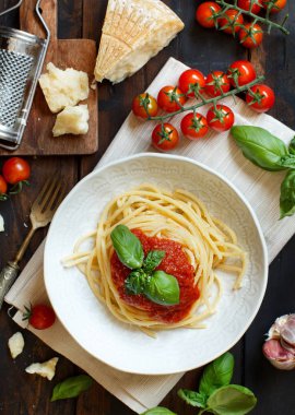 Spagetti makarna domates sosu, fesleğen ve ahşap bir masa üzerine peynir ile