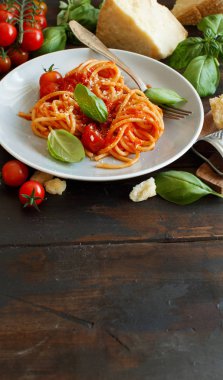 Spagetti makarna domates sosu, fesleğen ve ahşap bir masa üzerine peynir ile