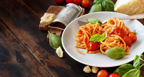 Spagetti makarna domates sosu, fesleğen ve ahşap bir masa üzerine peynir ile