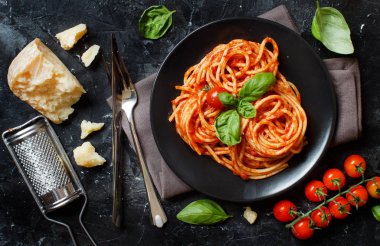 Spagetti makarna domates sosu, fesleğen ve karanlık bir tablo peynir ile