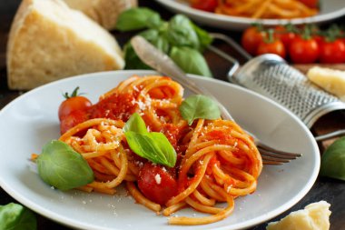 Spagetti makarna domates sosu, fesleğen ve ahşap bir masa üzerine peynir ile