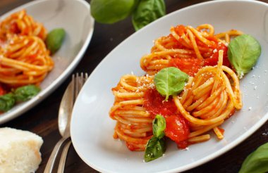 Spagetti makarna domates sosu, fesleğen ve ahşap bir masa üzerine peynir ile