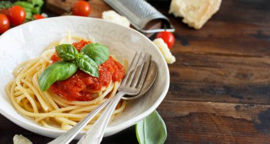Spagetti makarna domates sosu, fesleğen ve ahşap bir masa üzerine peynir ile