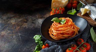 Spagetti makarna domates sosu, fesleğen ve karanlık bir tablo peynir ile