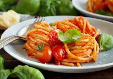 Spagetti makarna domates sosu, fesleğen ve ahşap bir masa üzerine peynir ile