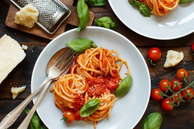 Spagetti makarna domates sosu, fesleğen ve karanlık bir tablo peynir ile