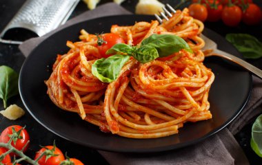 Spagetti makarna domates sosu, fesleğen ve karanlık bir tablo peynir ile