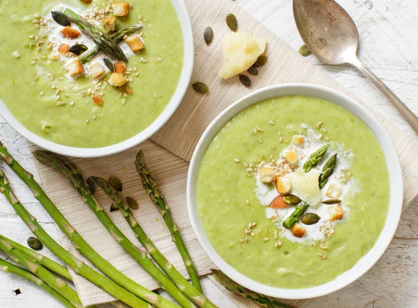 Creamy asparagus and potatoes soup puree on a wooden table