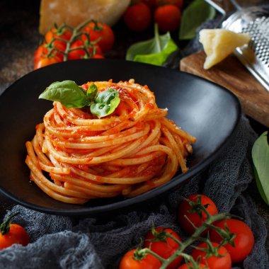 Spagetti makarna domates sosu, fesleğen ve karanlık bir tablo peynir ile