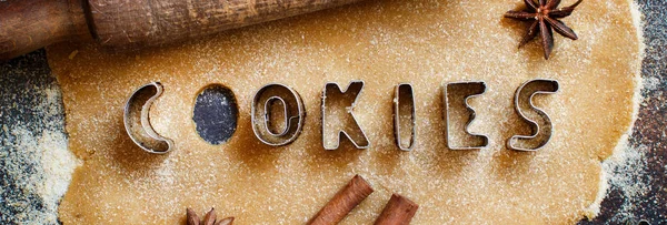 Making cookie letters  in a dough on a dark table