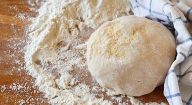 Mutfak masasında bir havlu ve un ile hamur