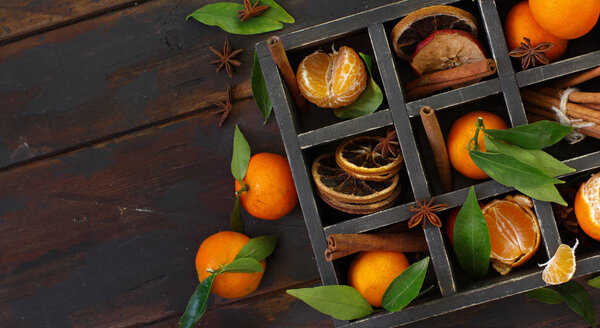 Mandarins  and spices in a box on a dark wooden background