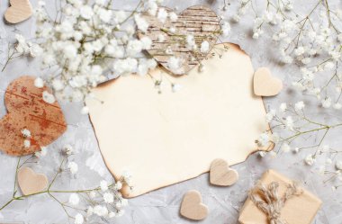 Küçük beyaz çiçekler ve kalpleri gri bir arka plan üzerinde hediye kutusu