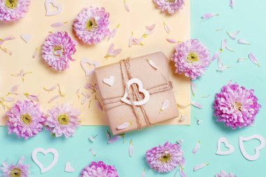 Pastel pembe arka plan üzerinde kalpleri ve hediye kutusu ile çiçek kompozisyon