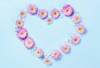  Pembe çiçek pastel mavi bir arka plan üzerinde yapılan kalp simgesi