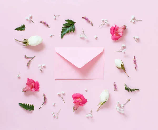 Blumen und Umschlag auf hellrosa Hintergrund — Stockfoto