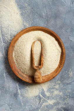 Çiğ pişmemiş fonio tohumları ve gri arkaplan görünümünde bir kaşık fotokopi alanı ile