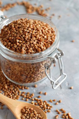 Kavanozda çiğ karabuğday taneleri ve kaşıkla yakın çekim. 