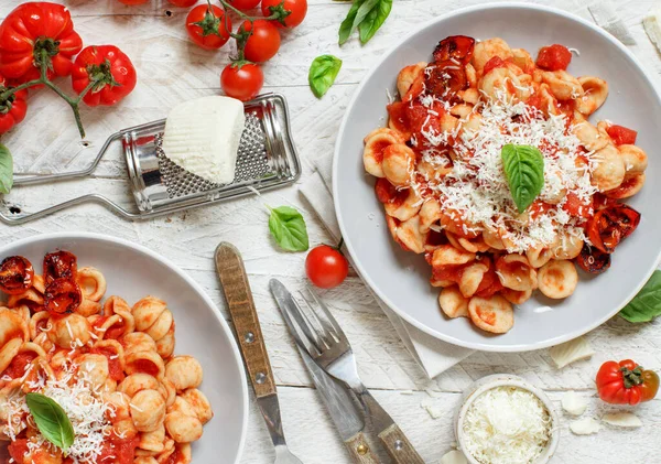 Güney İtalya makarnası, domates sosu ve beyaz ahşap bir masa üzerindeki cacioricotta peyniri manzaralı. 