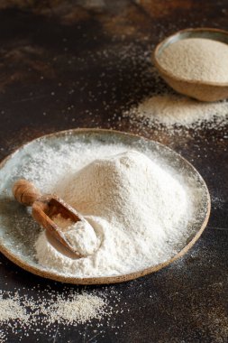 Çiğ fonio unu ve koyu arka planda kaşıkla tohumlar. Alternatif un