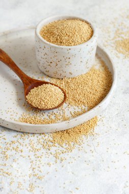 Beyaz bir masaya yakın bir kaşıkla bir kase çiğ Amaranth Grain.