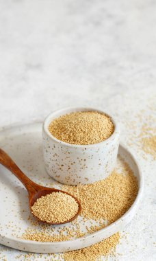 Beyaz bir masaya yakın bir kaşıkla bir kase çiğ Amaranth Grain.