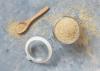 Gri masa manzaralı cam kavanoz dolusu çiğ beyaz kinoa tohumu.