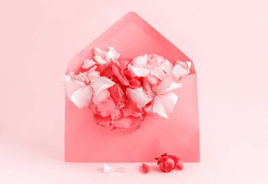 Pembe arka planda çiçeklerle dolu kırmızı bir zarf.