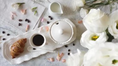 Kahve fincanı ve kruvasan manzaralı kahvaltı tepsisi.