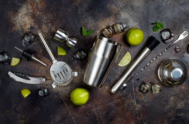 Bartender tools, lime, mint and ice on a dark table top view clipart